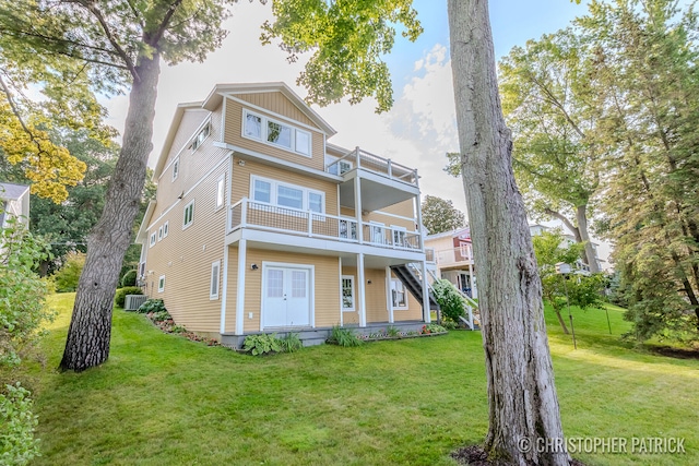 rear view of property with stairway, a lawn, a balcony, and central air condition unit