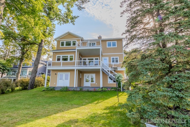 rear view of house with french doors, a lawn, a chimney, and a balcony