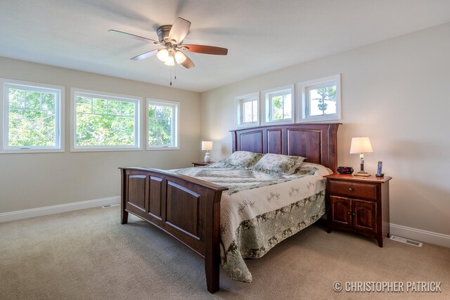 bedroom with a ceiling fan, visible vents, light carpet, and baseboards