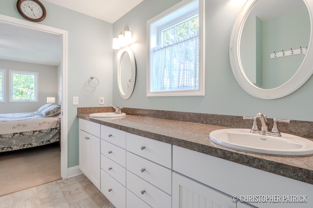 ensuite bathroom featuring double vanity, connected bathroom, and a sink