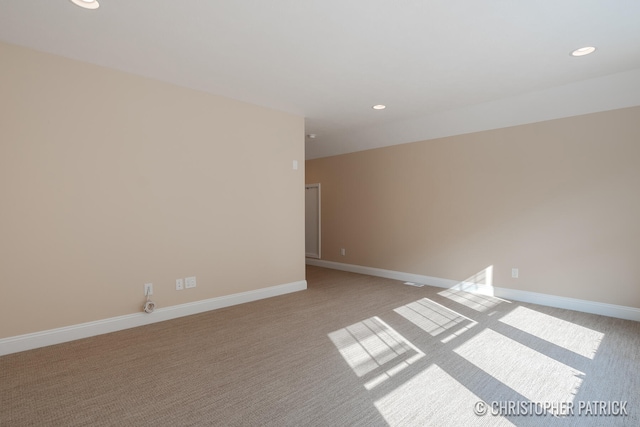 spare room featuring recessed lighting, light colored carpet, and baseboards