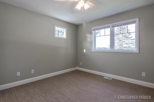 carpeted empty room featuring a ceiling fan, visible vents, and baseboards