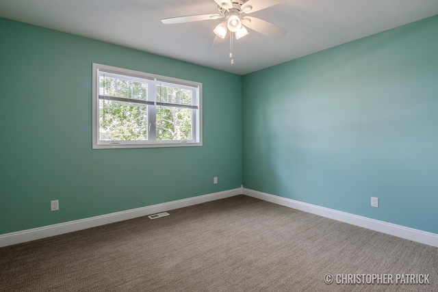 carpeted empty room featuring a ceiling fan, visible vents, and baseboards