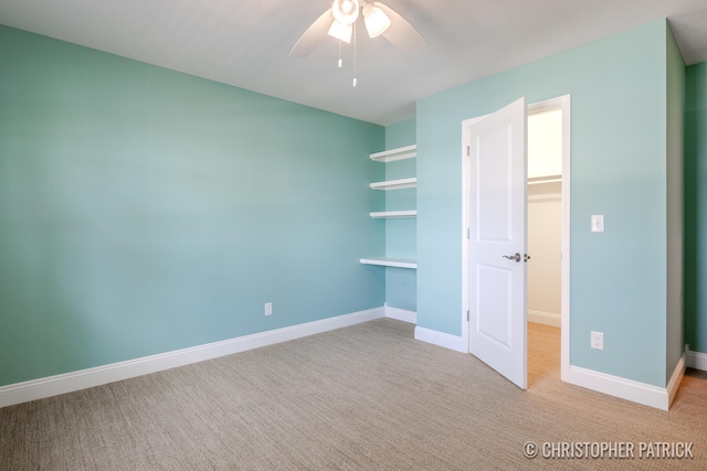 unfurnished bedroom featuring carpet floors, a closet, a spacious closet, a ceiling fan, and baseboards