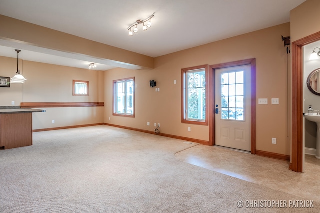 entryway with baseboards and light colored carpet