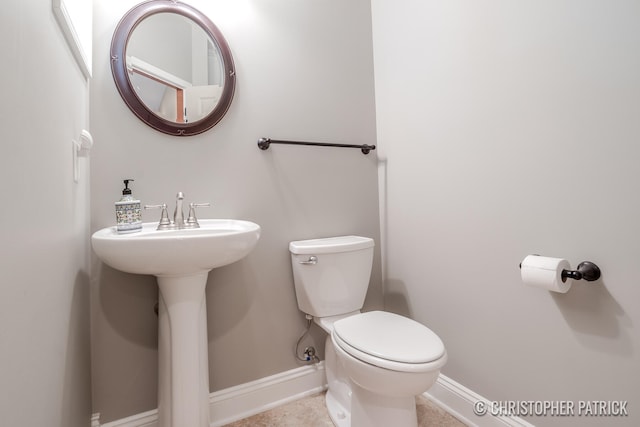 bathroom featuring toilet, baseboards, and a sink