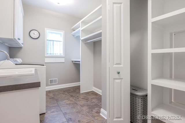 washroom with cabinet space, independent washer and dryer, visible vents, and baseboards