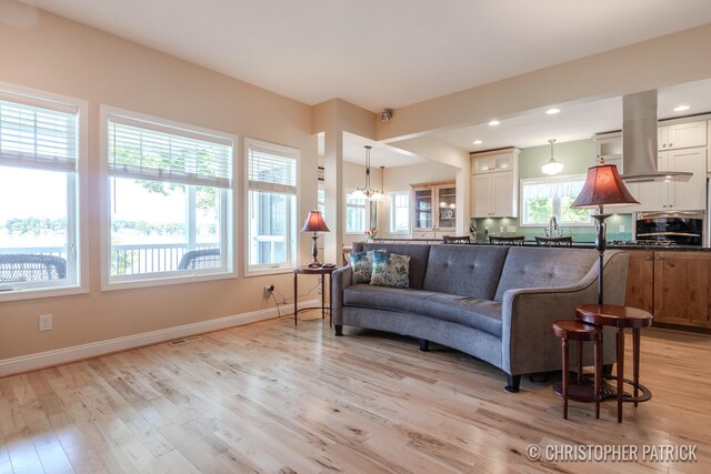 living room with light wood-style floors, recessed lighting, baseboards, and an inviting chandelier