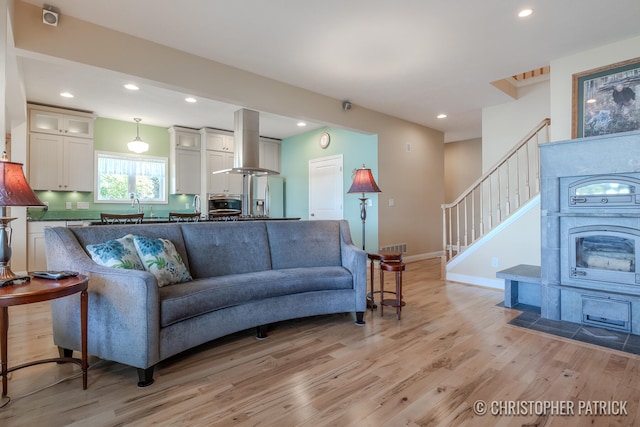 living room with light wood-style flooring, stairway, baseboards, and recessed lighting