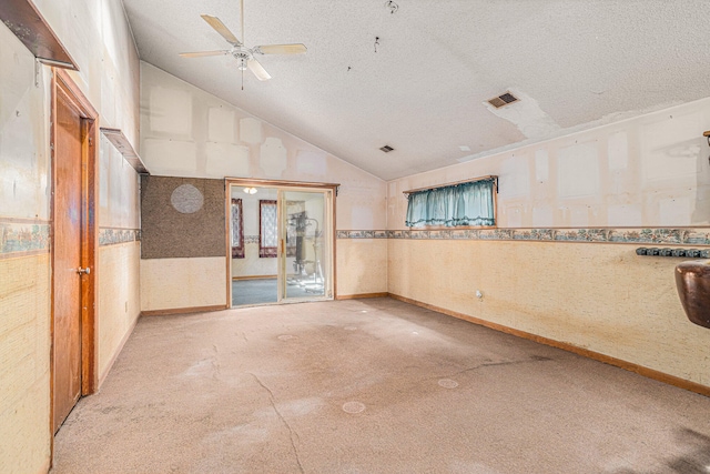 unfurnished room featuring ceiling fan, lofted ceiling, a textured ceiling, and carpet floors