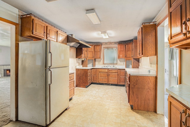 kitchen featuring sink, white refrigerator, backsplash, and exhaust hood