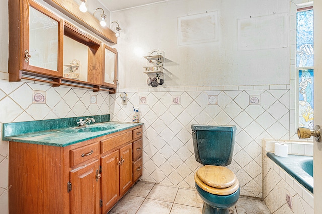 bathroom featuring tile patterned floors, vanity, tile walls, toilet, and a tub