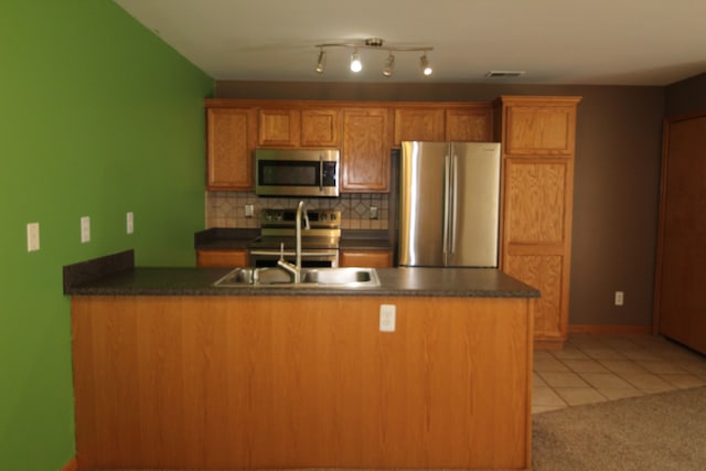 kitchen with sink, stainless steel appliances, backsplash, kitchen peninsula, and light tile patterned flooring