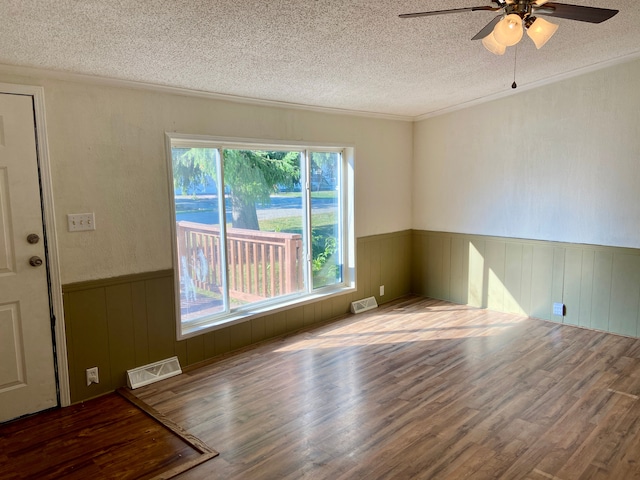 empty room featuring a textured ceiling, hardwood / wood-style flooring, ceiling fan, and ornamental molding