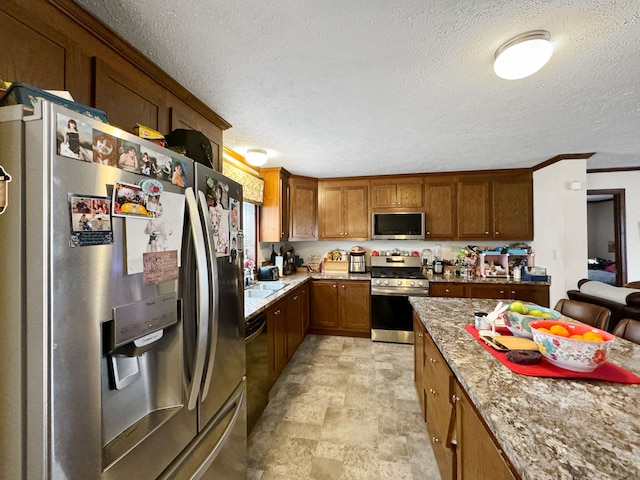 kitchen with light stone counters, stainless steel appliances, and a textured ceiling