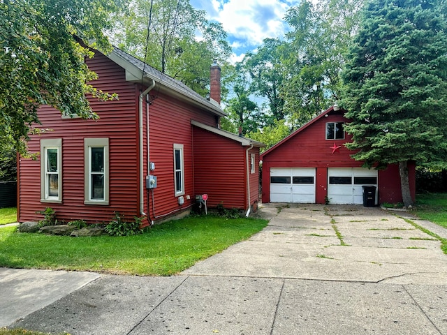 view of home's exterior with an outbuilding, a garage, and a lawn