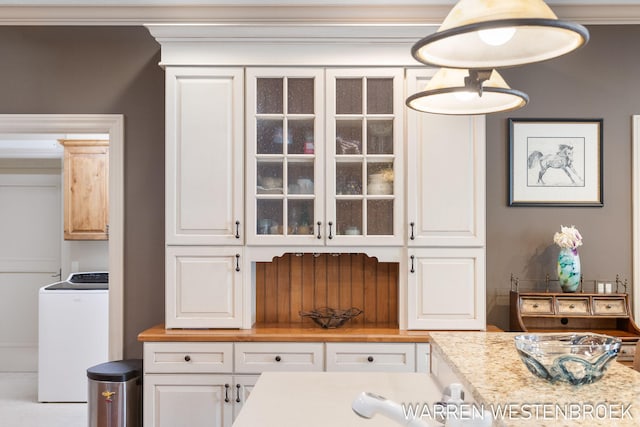 interior space featuring washer / clothes dryer, crown molding, and white cabinets