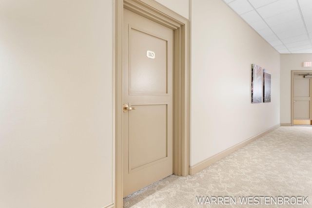 hallway with a paneled ceiling and light colored carpet