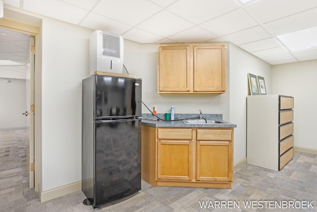 kitchen with a drop ceiling, black fridge, sink, and light carpet