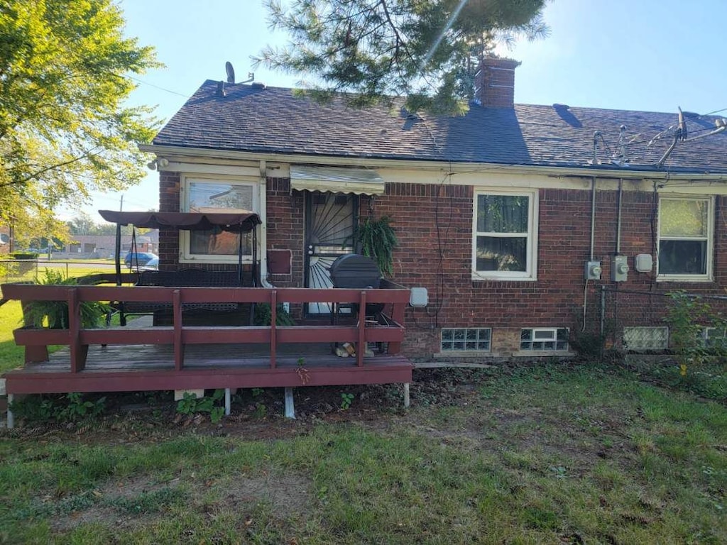 18829 Kelly Rd, Detroit, MI 48224 - rear view of house with a chimney, a deck, brick siding, and a yard