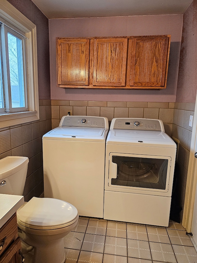 washroom featuring washer and dryer, light tile patterned flooring, and tile walls