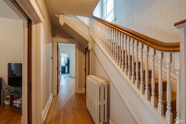 stairs with hardwood / wood-style flooring and radiator