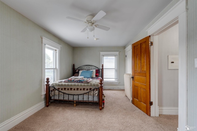 carpeted bedroom featuring multiple windows and ceiling fan