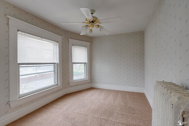 empty room with carpet flooring, radiator heating unit, and ceiling fan