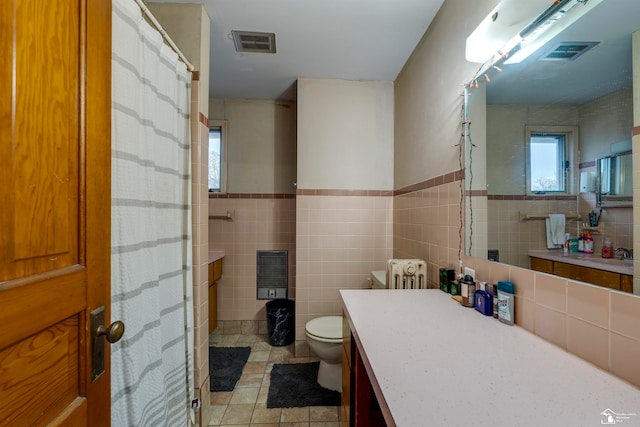 bathroom with tile patterned floors, toilet, and tile walls