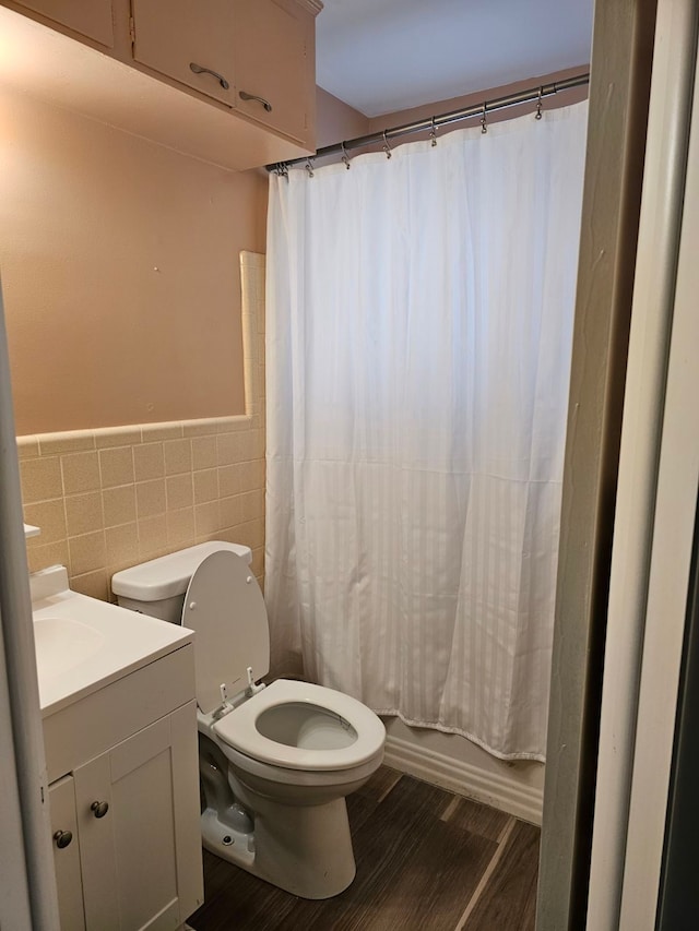 full bathroom with hardwood / wood-style floors, vanity, toilet, tile walls, and shower / tub combo