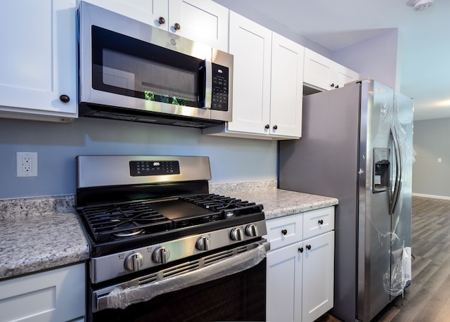 kitchen with light stone counters, white cabinetry, stainless steel appliances, and dark hardwood / wood-style floors