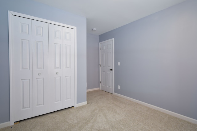 unfurnished bedroom with light colored carpet and a closet