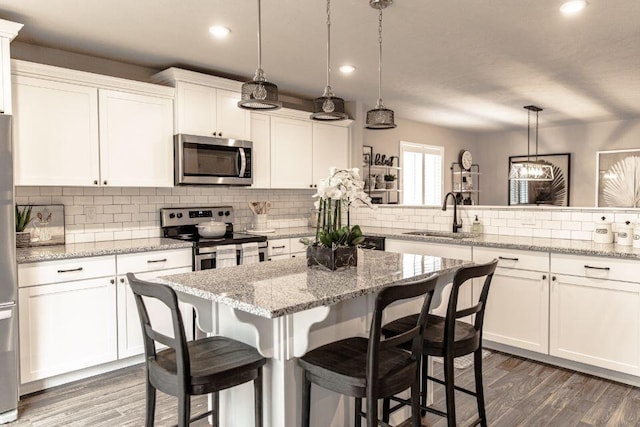 kitchen featuring white cabinetry, sink, pendant lighting, and stainless steel appliances