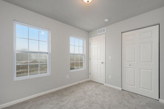 unfurnished bedroom with light carpet and a closet