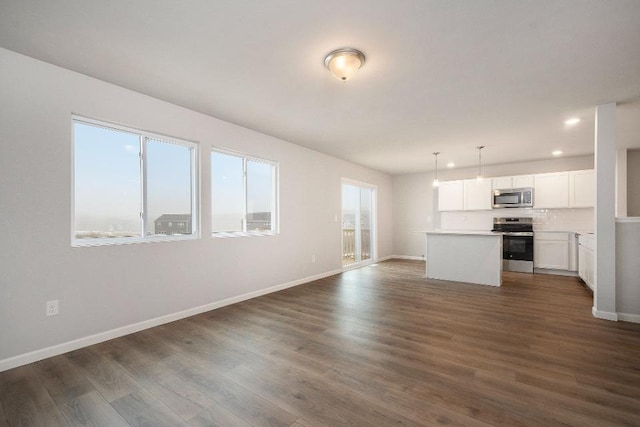 unfurnished living room featuring dark hardwood / wood-style flooring and a wealth of natural light