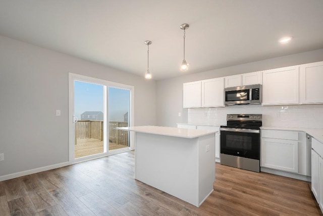 kitchen featuring hanging light fixtures, a kitchen island, stainless steel appliances, decorative backsplash, and white cabinets