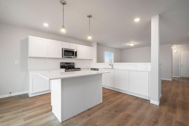 kitchen featuring white cabinetry, pendant lighting, wood-type flooring, and stainless steel appliances