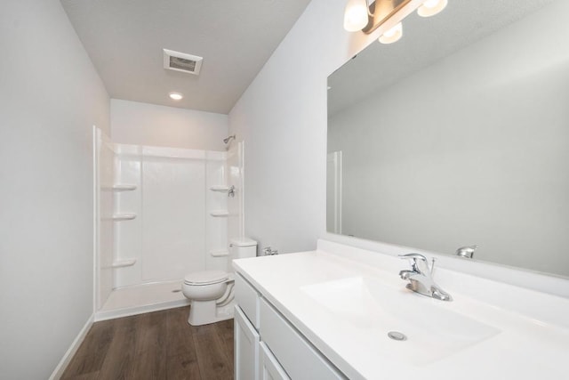 bathroom with wood-type flooring, toilet, vanity, and a shower