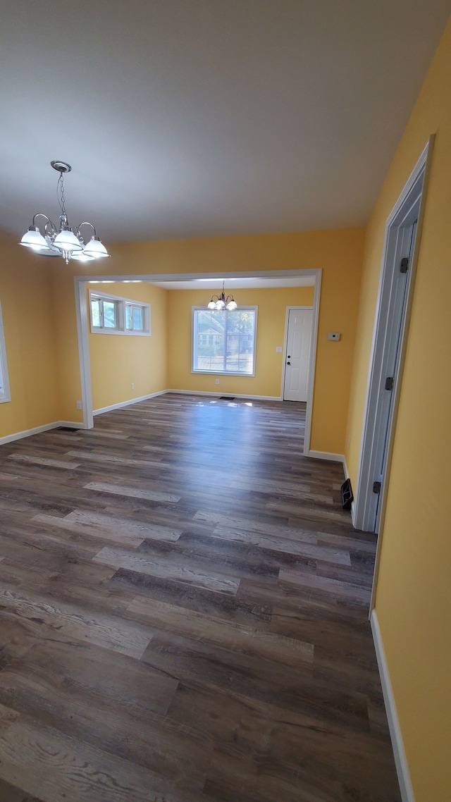 unfurnished room with a chandelier and dark wood-type flooring