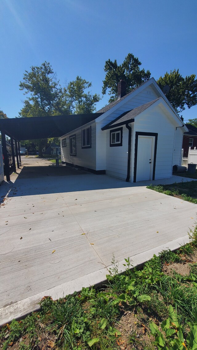 view of front of property with driveway, a chimney, and a carport