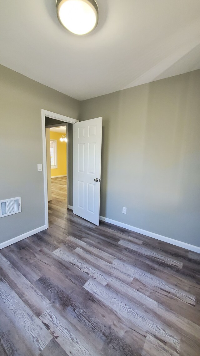 empty room with dark wood-type flooring and baseboards