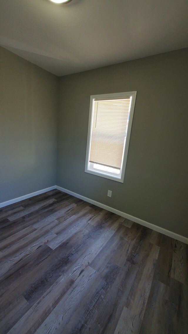 unfurnished room with dark wood-style flooring and baseboards