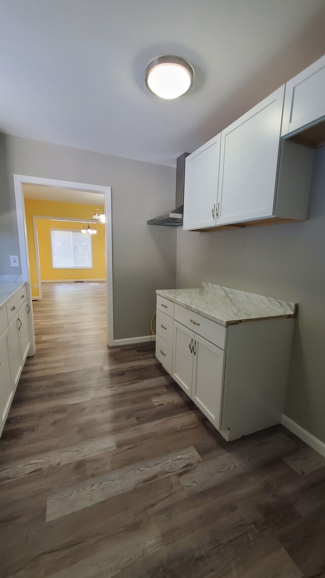 laundry area featuring dark wood-type flooring, baseboards, and a chandelier