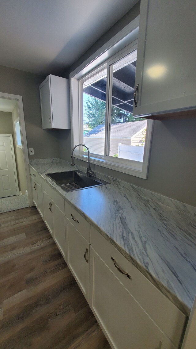 kitchen featuring a sink, light countertops, dark wood finished floors, and white cabinets