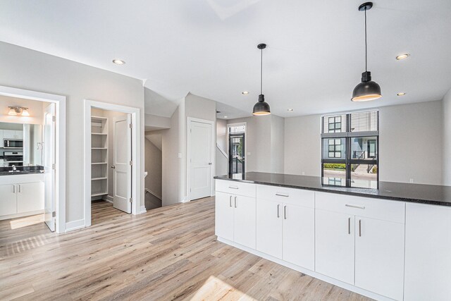 kitchen featuring pendant lighting, white cabinets, dark stone countertops, and light hardwood / wood-style flooring