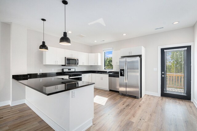 kitchen with white cabinets, decorative light fixtures, a healthy amount of sunlight, and appliances with stainless steel finishes