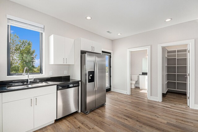 kitchen with white cabinets, appliances with stainless steel finishes, dark hardwood / wood-style floors, and sink