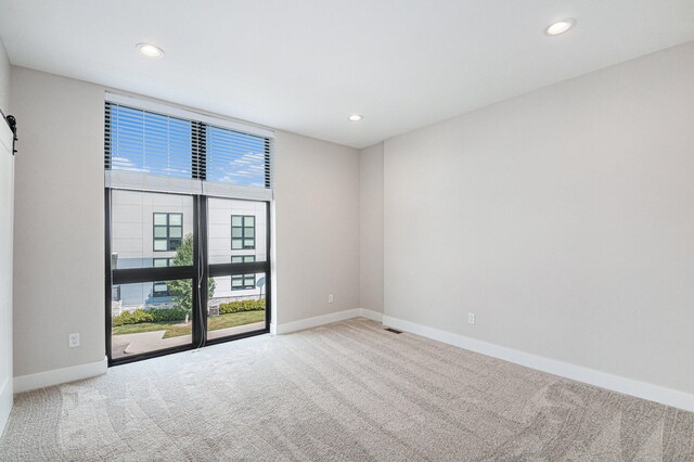 carpeted empty room featuring a barn door