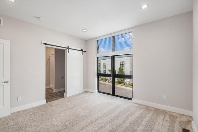 unfurnished bedroom featuring access to outside, a barn door, and carpet floors