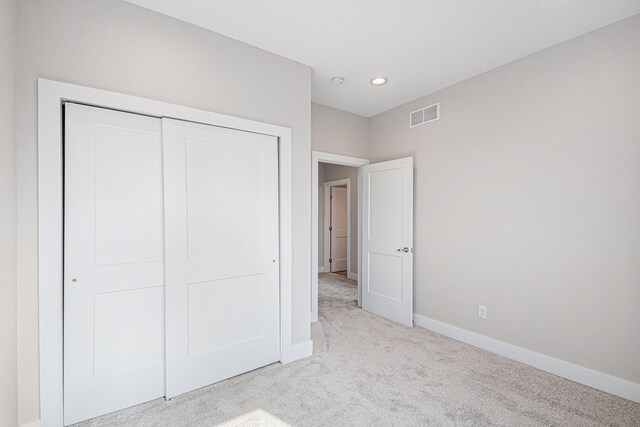 unfurnished bedroom featuring light carpet and a closet